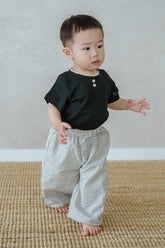 Toddler wearing Avauma Breeze Jogger Pants in vintage check, standing on mat with black top.